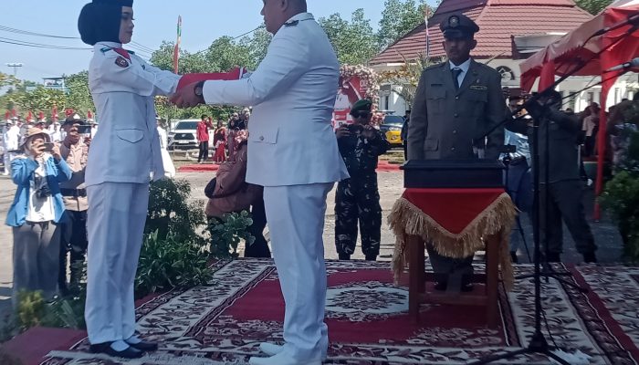 Camat Bukit Batu Serahkan Bendera Merah putih Kepada salah satu petugas pengibar.